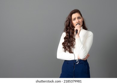 Attractive Female Conference Speaker During Presentation, Holds Microphone And Makes Some Gestures, Isolated On Gray