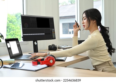 Attractive female content creator using laptop, working with footage and sound in creative office studio - Shutterstock ID 2254636839