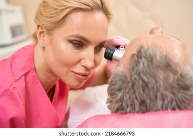Attractive female dermatologist-oncologist performs an examination with a dermatoscope