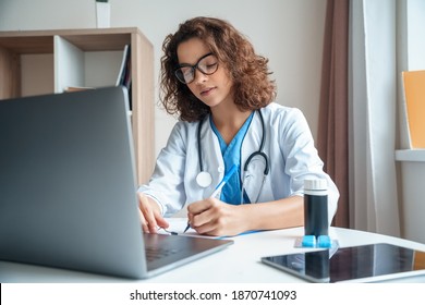 Attractive Female Doctor Make Online Video Call Consult Patient On Laptop. Medical Assistant Young Woman Therapist Videoconferencing To Web Camera. Telemedicine Concept. Online Doctor Appointment.