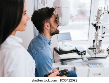 Attractive female doctor  ophthalmologist is checking the eye vision of handsome young man in modern clinic. Doctor and patient in ophthalmology clinic. - Shutterstock ID 1038422092