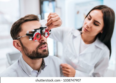 Attractive female doctor  ophthalmologist is checking the eye vision of handsome young man in modern clinic. Doctor and patient in ophthalmology clinic.