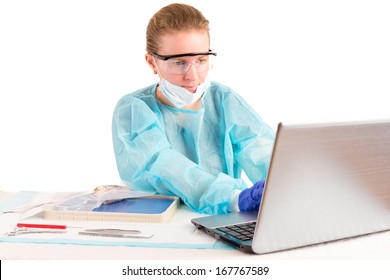 Attractive female doctor or pathologist seated at a desk in the laboratory entering information on a laptop computer