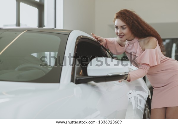 Attractive\
female driver looking inside a new sportscar, shopping for\
automobile. Gorgeous woman examining modern cars at the dealership,\
copy space. Driving, transportation\
concept