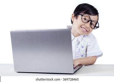 Attractive Female Elementary School Student Smiling At Camera And Using A Laptop, Isolated On White Background