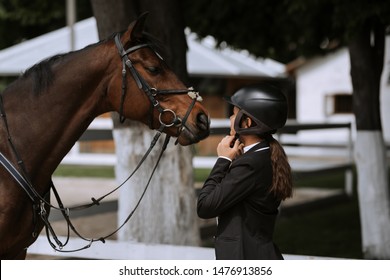 Attractive female equestrian in riding helmet looking at horse in horse club. - Powered by Shutterstock