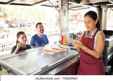 Attractive female food truck cook taking orders from her customers and selling hot dogs - Powered by Shutterstock