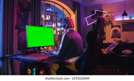 Attractive Female Gamer Playing Online Video Game With A Mock Up Green Screen On Her Powerful Computer. Room And PC Have Colorful Neon Led Lights. Fun Evening At Home In Modern Apartment.