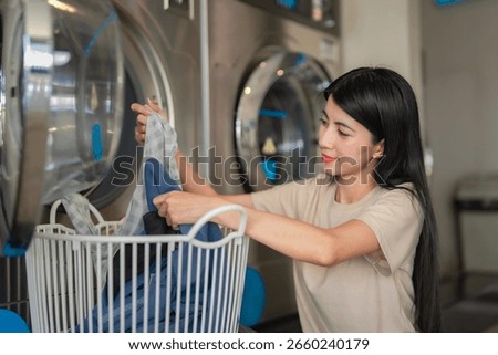 Attractive female loading machine at local coin-operated laundry. Cleanliness and modern urban life.