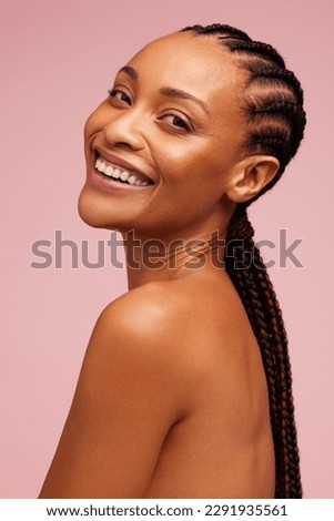 Attractive female model with glowing skin looking at camera and smiling. African american woman with flawless skin against pink background.