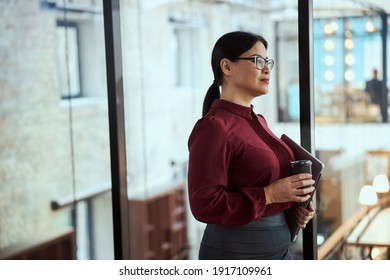 Attractive female person looking forward while spending coffee break in the hall