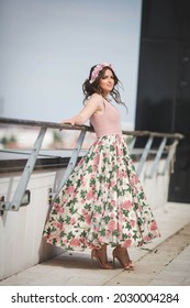 An Attractive Female In A Pink Dress With A Flower Print On The Skirt And Flower Hairband