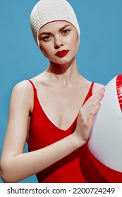 Attractive Female Swimmer In A Red Swimsuit With A Striped Ball. Close-up Portrait