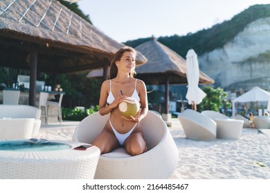Attractive female tourist with coconut resting at Bahamas seashore enjoying summer recreation vacations on tropical island, Caucaisan woman with exotic beverage resting in lounge zone at beach - Shutterstock ID 2164485467