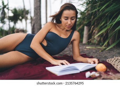 Attractive female tourist in trendy swimwear reading literature best seller during leisure pastime an sandy coastline beach, Caucaisan woman interested in novel poetry book - resting at seashore