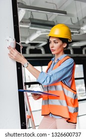 Attractive Firefighter Checking Fire Alarm While Holding Clipboard