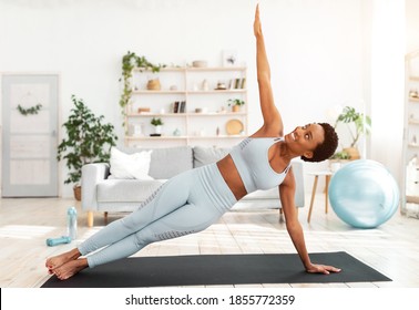 Attractive fit black lady standing in side plank on sports mat at home. Motivated African American woman doing strength exercises, aerobics or yoga. Healthy lifestyle concept - Powered by Shutterstock