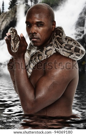 Attractive Fit Black Man with Python Standing in Lake in front of Waterfall