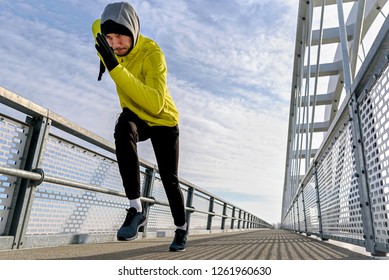 Attractive Fit Man Running Fast Along Big Modern Bridge. Exercising, Jogging, Sport, Winter. Male Athlete Running.