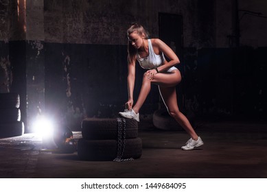 Attractive Fit Woman Athlete Tying Shoelaces On Tires, Fit Woman Exercising With Big Tire.