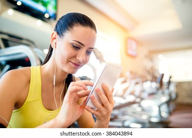 Attractive fit woman in a gym with smart phone