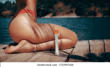 Attractive fit woman with sun cream protection bottle outdoors by the water.Copy space included - Shutterstock ID 1752997634