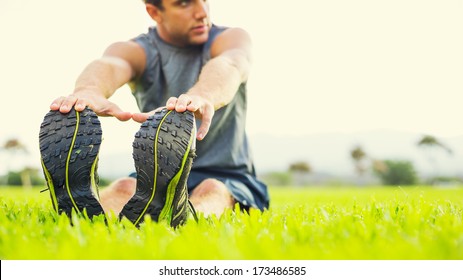 Attractive Fit Young Man Stretching Before Exercise, Sunrise Early Morning Backlit. Shallow Depth Of Field, Focus On Shoes