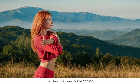 Attractive fit young woman having morning training on beautiful mountain background, Summer sunrise: girl's nature workout amid mountain fitness routine