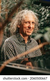 attractive flirtatiously smiling man 65 years old gray curly hair plays grand piano and looks at camera with smile. Real people, photo