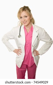 Attractive Friendly Smiling Blond Lady Doctor In Lab Coat With Hands On Hips Over White