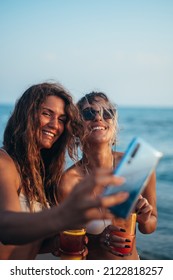 Attractive Friends Enjoying Vacation Together And Taking Selfie On The Beach Using Smartphone And Drinking Cocktails