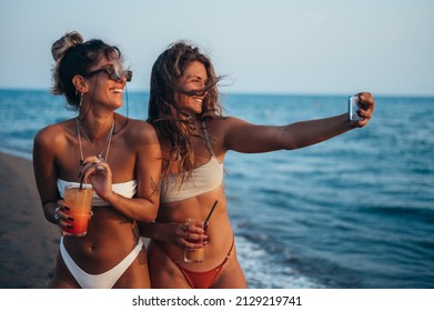 Attractive Friends Enjoying Vacation Together And Taking Selfie On The Beach Using Smartphone And Drinking Cocktails