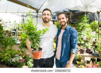 Attractive Gay Couple Hugging At The Nursery Garden Buying Together Small Trees And Plants For Their Home 