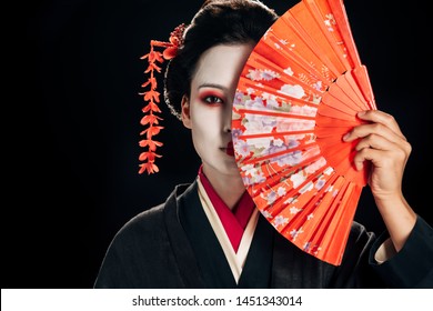 attractive geisha in black kimono with flowers in hair holding bright hand fan isolated on black - Powered by Shutterstock