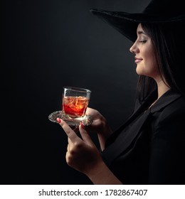 Attractive Girl With Alcoholic Drink In Frozen Glass. Beautiful Brunette In Black Hat Holding Glass With Cold Cocktail.