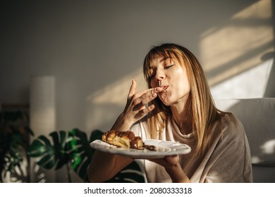 Attractive girl eating croissants in a bright room. Beautiful girl eating croissants with chocolate for breakfast