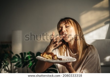 Attractive girl eating croissants in a bright room. Beautiful girl eating croissants with chocolate for breakfast
