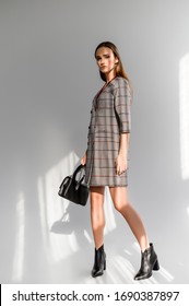 Attractive girl in a gray checkered dress on a white background

