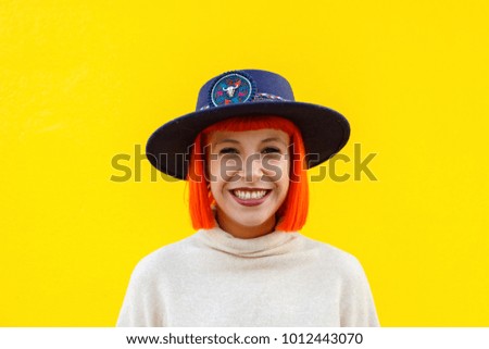 Attractive girl with a hat over a yellow wall