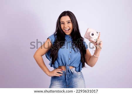 attractive girl holding a polaroid camera smiling at the viewer
