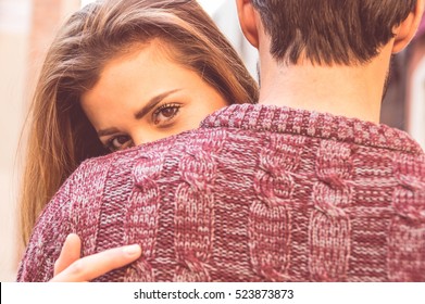 Attractive girl hugging her boyfriend and looking at the camera. Concept about love, people and lifestyle.