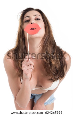 Attractive girl in jeans and bikini posing with paper red lips on wood stick, isolated on white background. Fun and joke concept