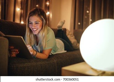 Attractive girl lying on sofa and using tablet. - Powered by Shutterstock