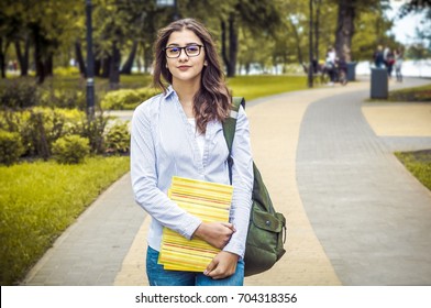 Attractive girl in the park. Indian woman in glasses with books