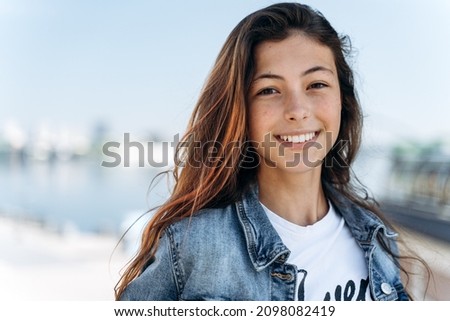 Attractive girl posing against the backdrop of the city. Cute girl - a teenager smiling, looking at the camera, close-up view.