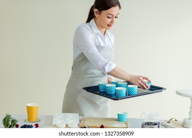 Attractive Girl Putting Cupcake Liner On The Oven Sheet At Home Kitchen. Close Up Photo.