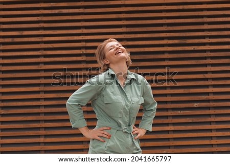 Attractive girl smiling, standing on wooden wall background