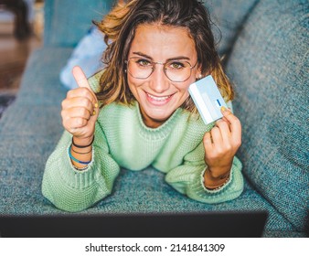 Attractive girl spending his time on shopping online - Young girl relaxing on couch while buying clothes with his credit card