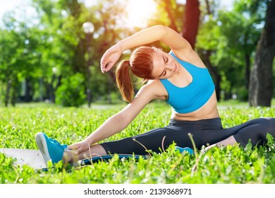 Attractive Girl In Sportswear Doing Yoga In Park. Young Woman Sitting In Yoga Pose On Green Grass. Sport Training Outdoor At Sunny Summer Day. Morning Stretching Exercises And Healthy Lifestyle.