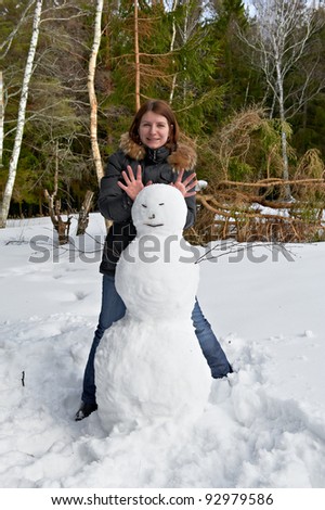 attractive girl standing beside a snowman